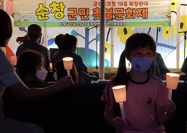 한 어린이가 촛불문화제에 참석해 양 손에 촛불을 들고 있다.