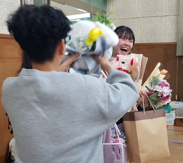 지난 8일 졸업식에서 꽃다발과 선물을 잔뜩 건네받은 여중 학생이 활짝 웃고 있다.
